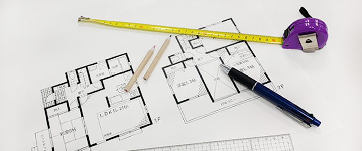 間取り図とメジャー、筆記用具が重なり置かれた画像